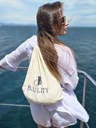 Frau Mit einem beigem Stoffbeutelrücksack mit goldenem BJULITY Logo auf einem Boot