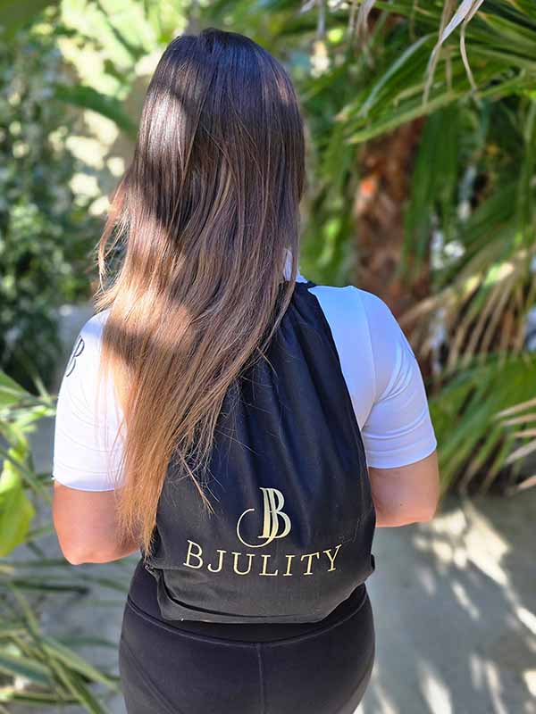 Frau Mit einem schwarzen Stoffbeutelrücksack mit goldenem BJULITY Logo